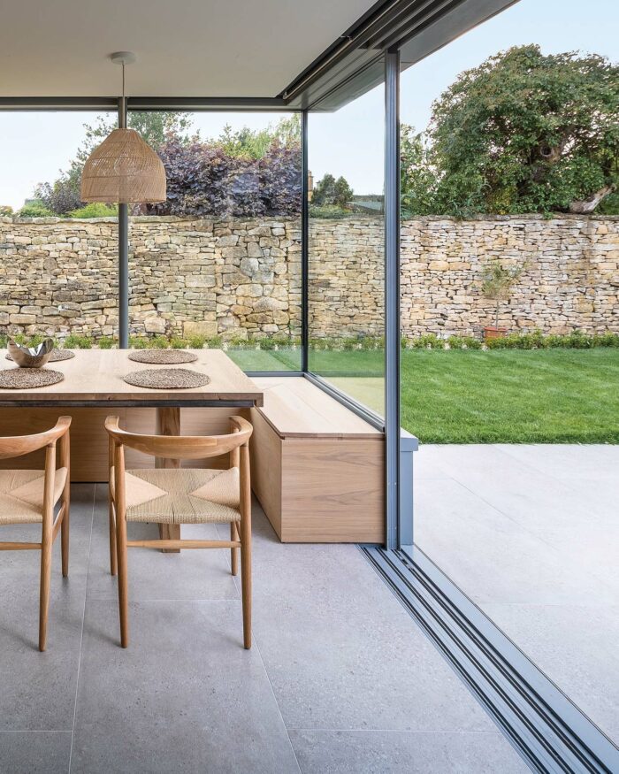 Interior dining area with patio doors leading to outdoor patio tiled with Kast Light Grey Porcelain stone effect tiles