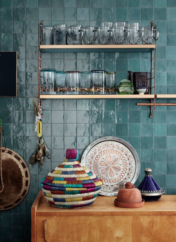 Petrol coloured Zellige wall tiles behind decorated kitchen shelves.