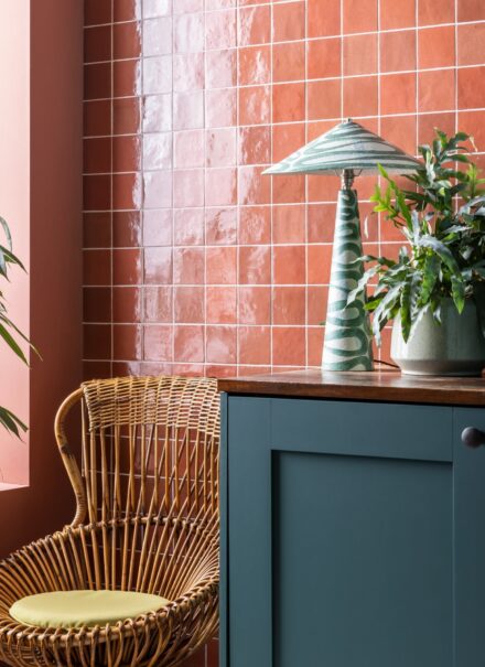 Pink, square shaped Zellige style tiles on a kitchen wall, reflecting the light.