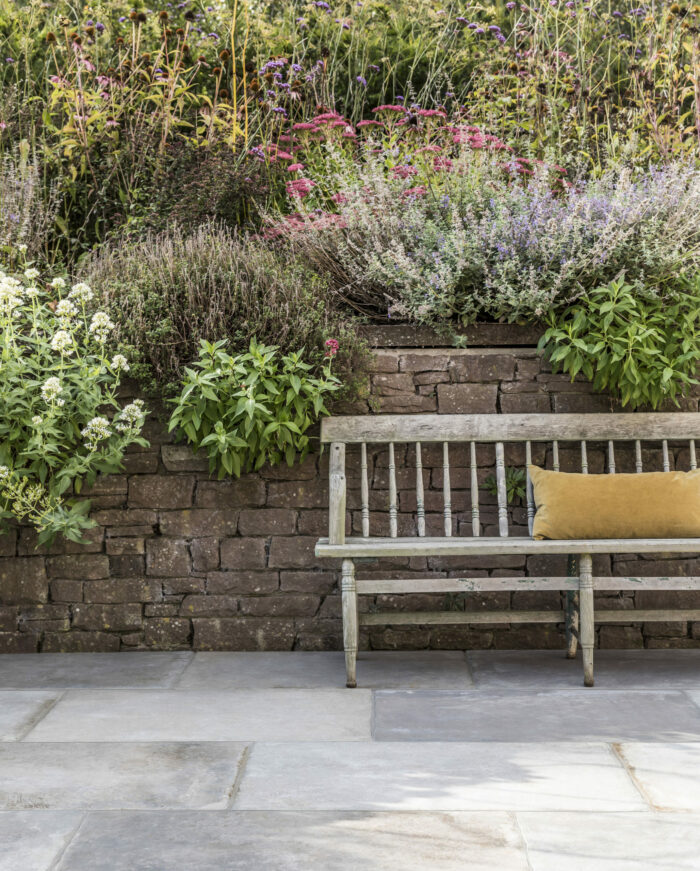Traditional courtyard with old stone and flowers. Patio laid with Mandarin Stone Wexford Grey porcelain outdoor stone effect tiles